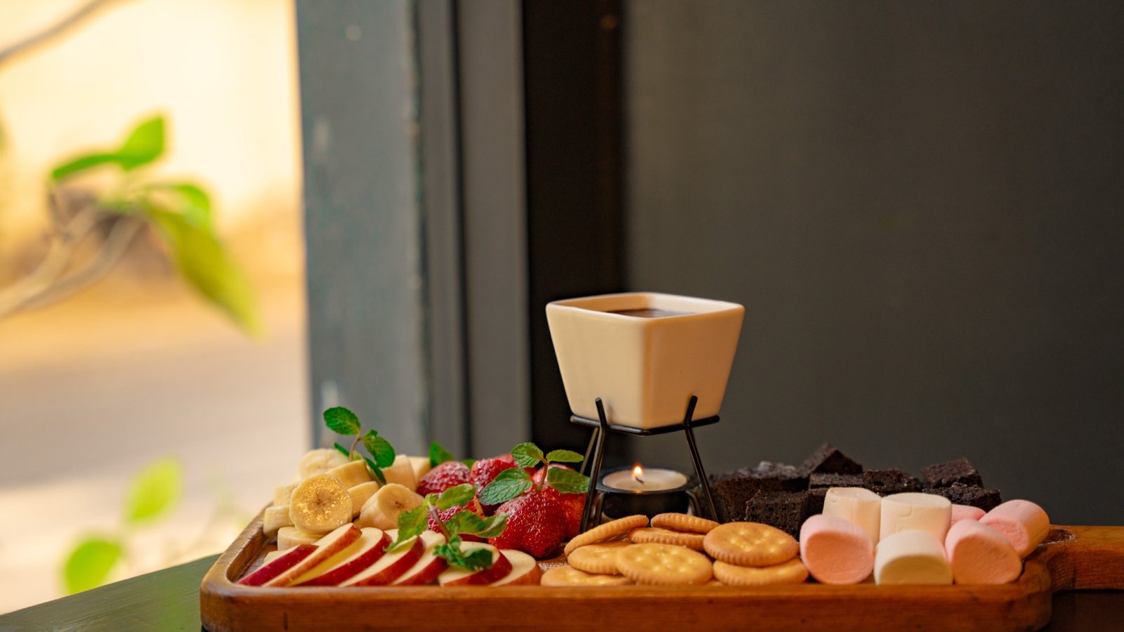 Chocolate fondue board with strawberries, bananas, biscuits and marshmallows