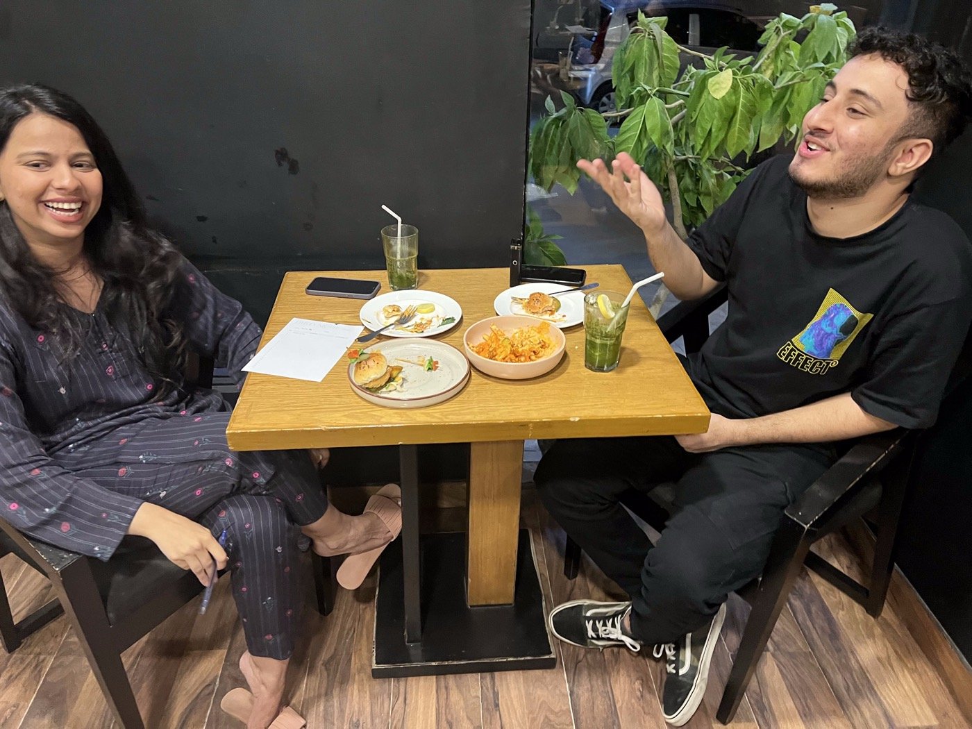 Two guests chatting at a table with mocktails and food