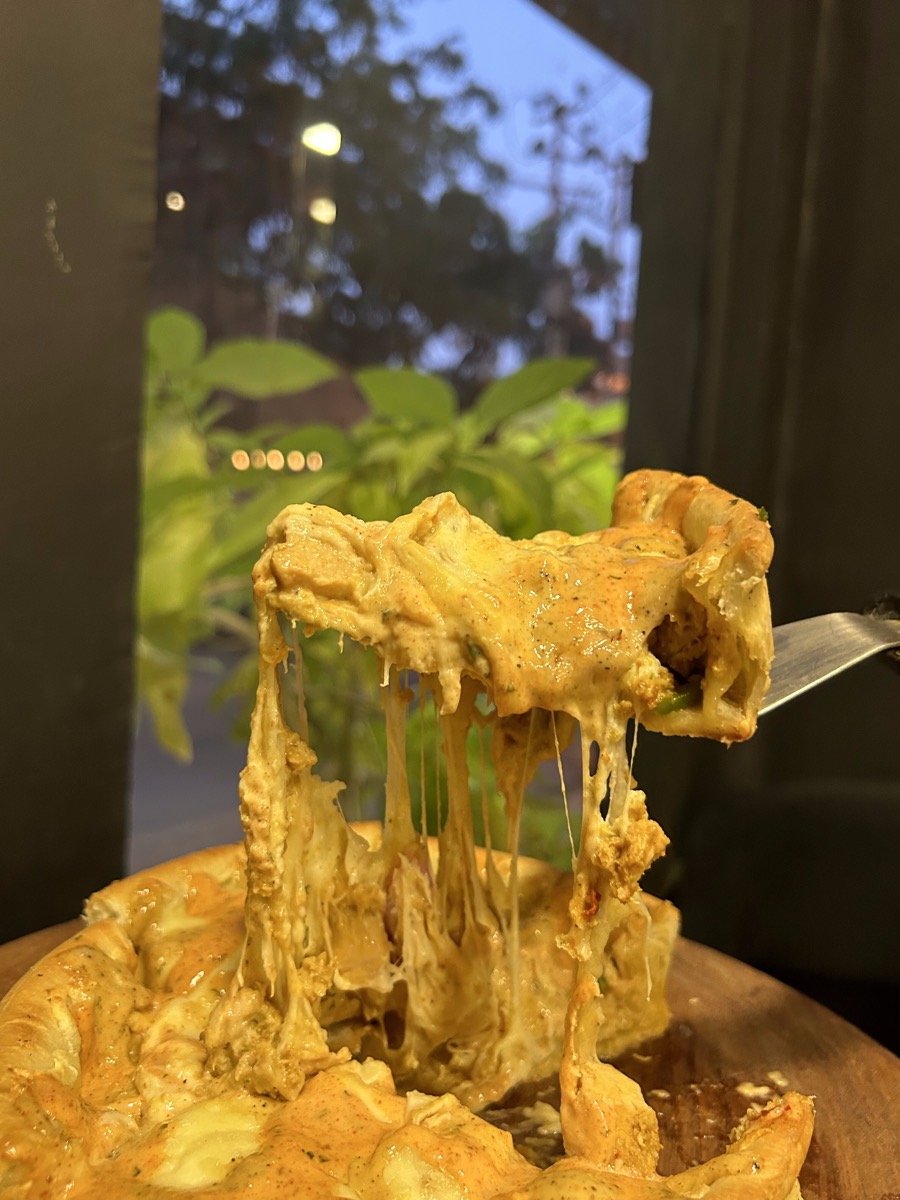 A slice of deep dish pizza being lifted with long strands of cheese