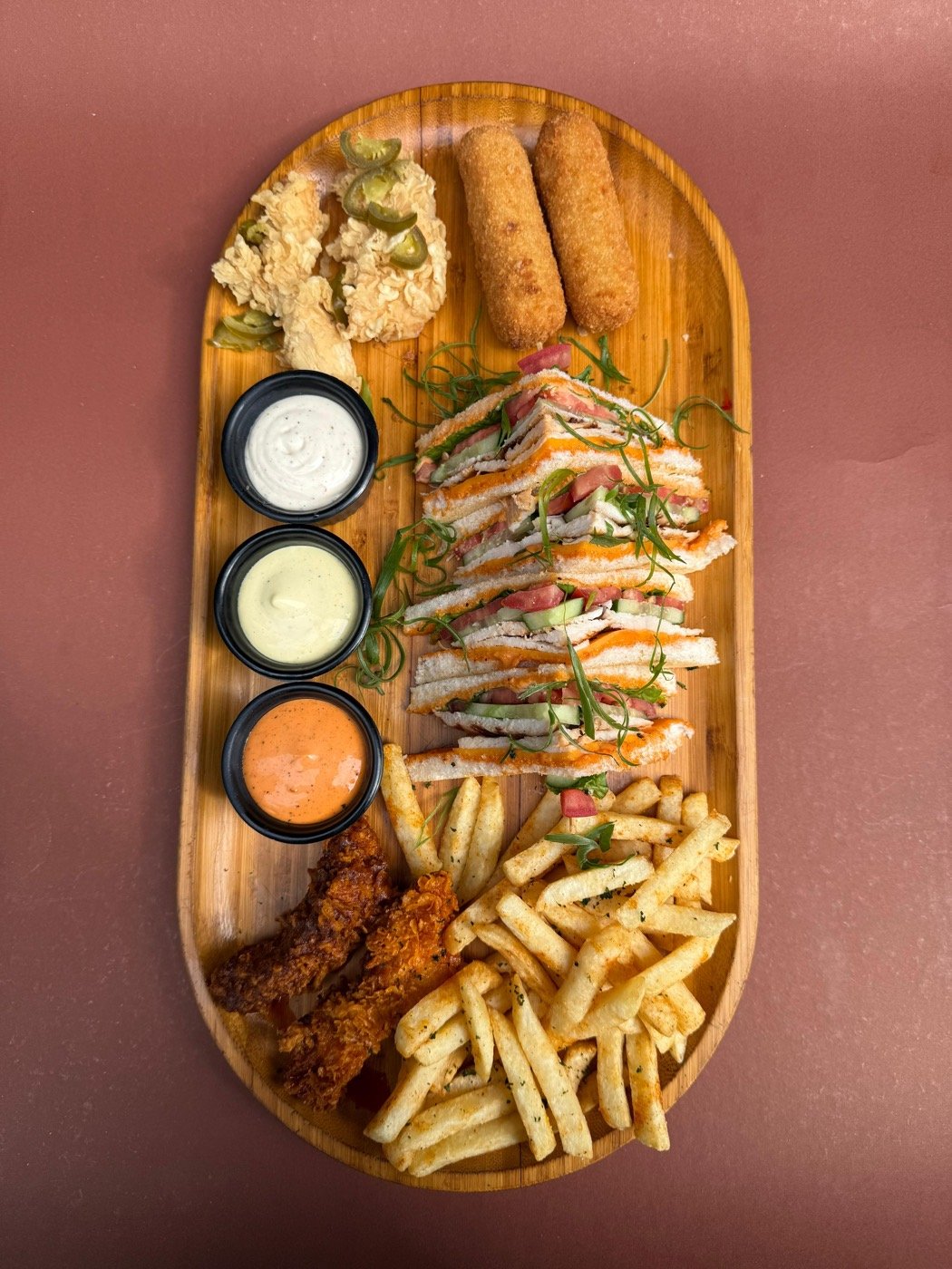 Appetizer platter with club sandwich, fries, chicken and three dips